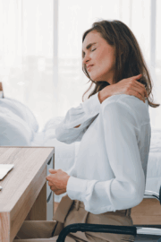 Woman raising laptop to eye level at desk
