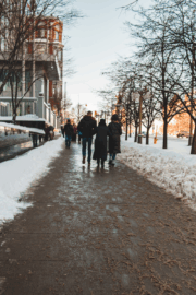 Person walking carefully on an icy Maine sidewalk wearing winter boots, symbolizing fall prevention and balance.