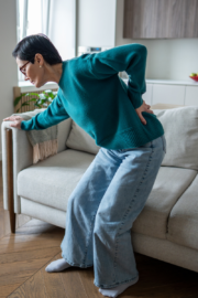 Person experiencing cold weather joint pain while holding their knee outdoors in winter.