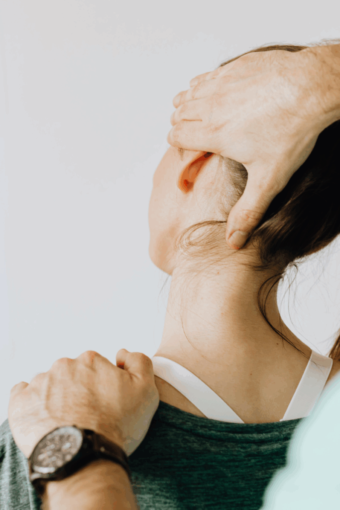 Physical therapist guiding patient through jaw and neck stretches.