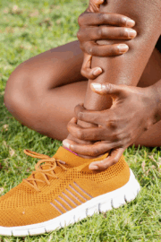 Runner holding shin while resting on Portland waterfront trail