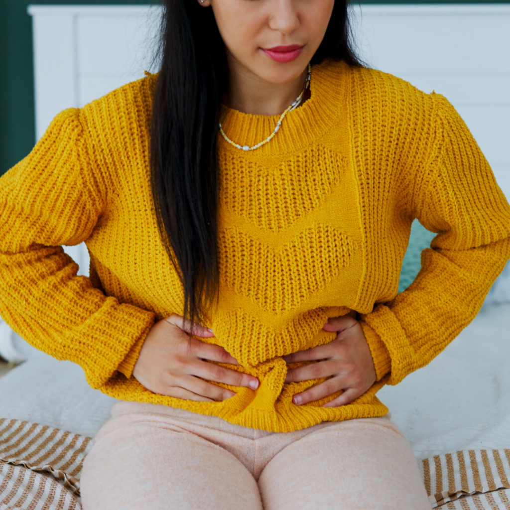 Woman holding her lower stomach, showing discomfort that may relate to pelvic floor problems.