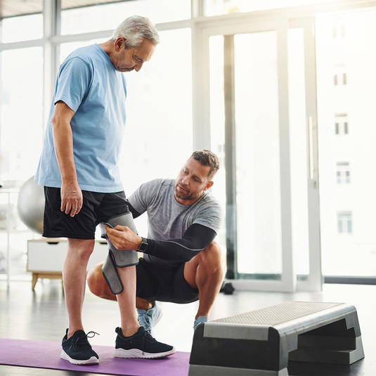Patient practicing gentle knee bending with a physical therapist during early knee replacement recovery.